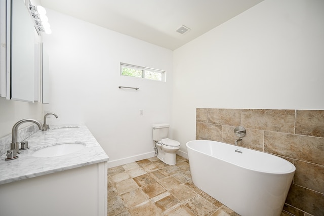 bathroom with tile walls, vanity, a bathtub, and toilet