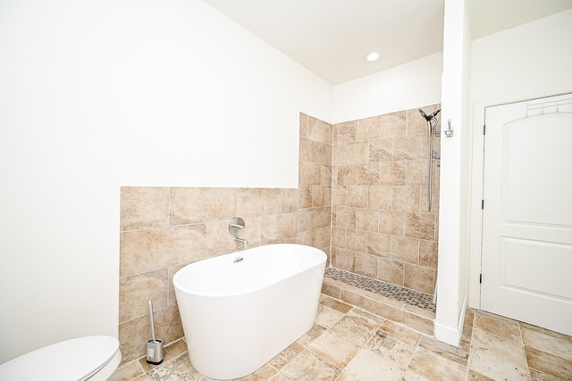 30626 Logger Ln, Magnolia, TX 77355 - bathroom with a freestanding tub, tiled shower, tile walls, stone tile floors, and toilet
