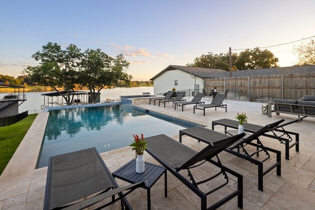 pool at dusk featuring a patio area and a water view