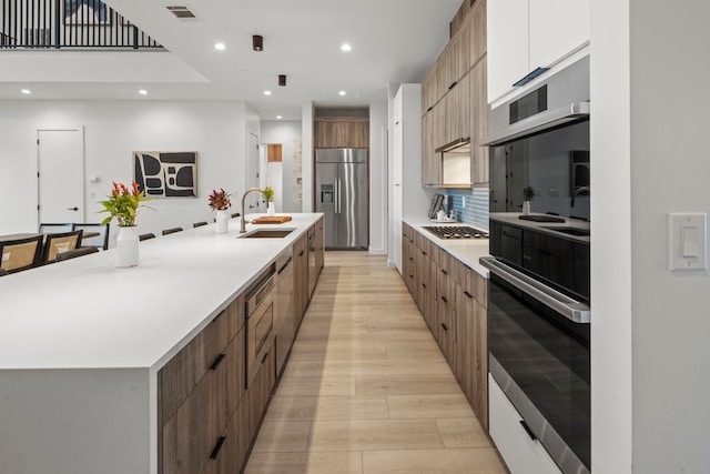 kitchen with tasteful backsplash, sink, white cabinetry, a large island, and stainless steel appliances