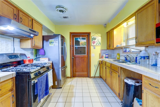 kitchen with decorative backsplash, light tile patterned floors, sink, tile counters, and stainless steel appliances