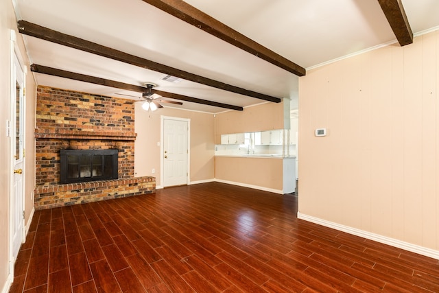 unfurnished living room with dark hardwood / wood-style floors, ceiling fan, beamed ceiling, and a brick fireplace