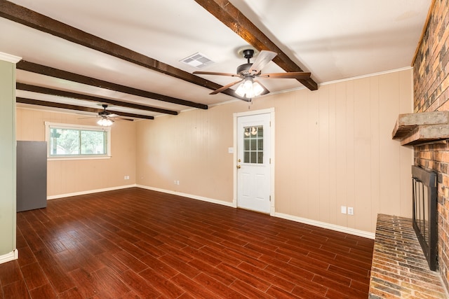 unfurnished living room featuring beamed ceiling, dark wood-type flooring, wooden walls, a fireplace, and ceiling fan