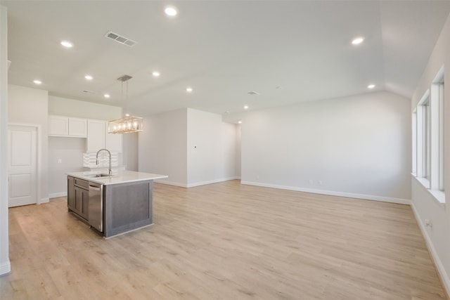 kitchen with lofted ceiling, an island with sink, white cabinetry, light hardwood / wood-style floors, and sink