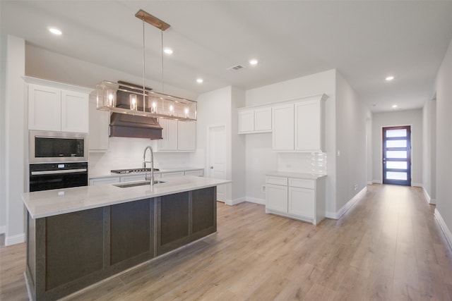 kitchen with white cabinets, decorative light fixtures, stainless steel appliances, and light hardwood / wood-style floors