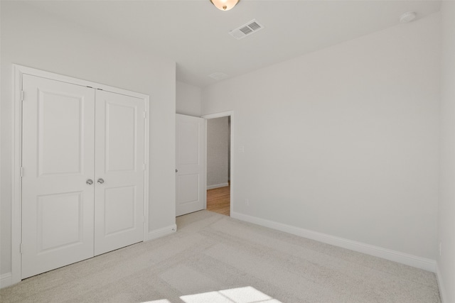 unfurnished bedroom featuring a closet and light colored carpet