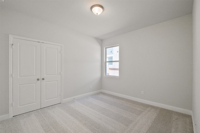 unfurnished bedroom with light carpet and a closet