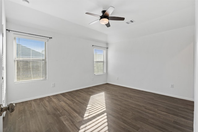 empty room with ceiling fan, a wealth of natural light, and dark hardwood / wood-style flooring