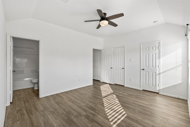 unfurnished bedroom with lofted ceiling, multiple closets, ensuite bath, ceiling fan, and dark hardwood / wood-style flooring