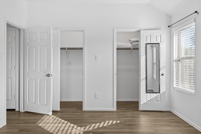 unfurnished bedroom featuring lofted ceiling, a spacious closet, and dark hardwood / wood-style flooring