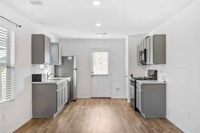 kitchen featuring light hardwood / wood-style flooring, stainless steel appliances, sink, and gray cabinetry