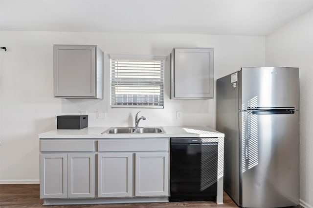 kitchen featuring stainless steel fridge, dishwasher, dark wood-type flooring, gray cabinets, and sink