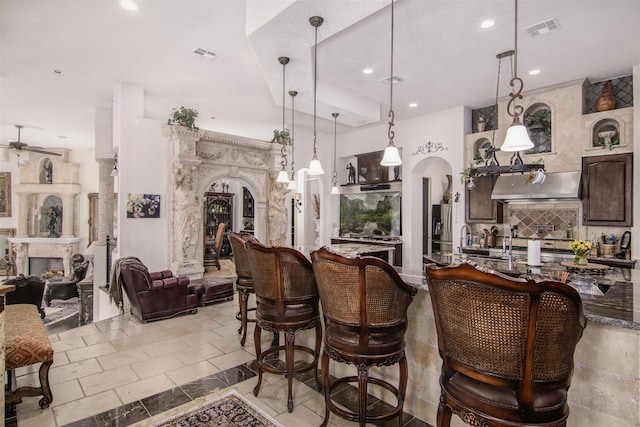 bar featuring ceiling fan, dark brown cabinets, decorative light fixtures, and backsplash