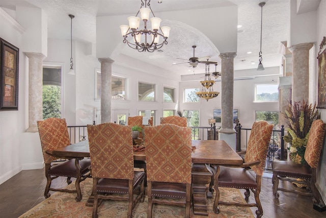 dining area featuring dark wood-type flooring, ornate columns, a textured ceiling, and ceiling fan with notable chandelier