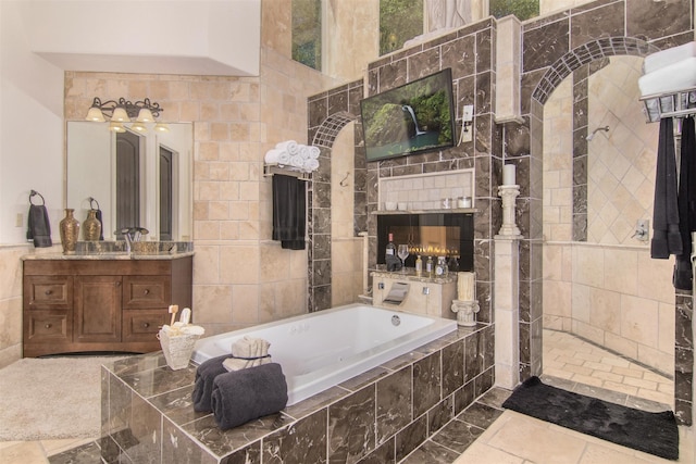 bathroom with vanity, tiled bath, and tile walls