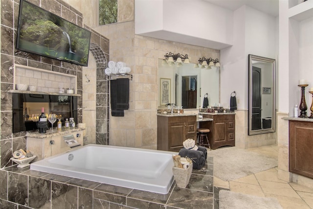 bathroom featuring vanity, tile walls, a high ceiling, and tiled bath