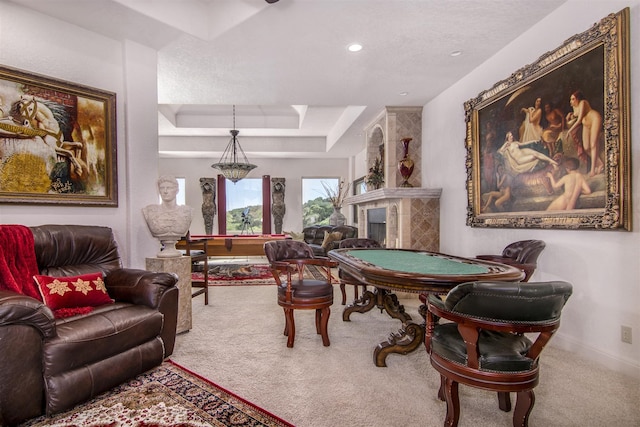 game room featuring carpet floors, a tile fireplace, and a raised ceiling