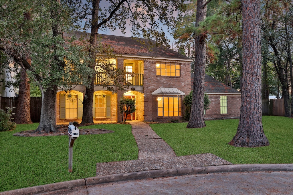 view of front of house with a balcony and a lawn