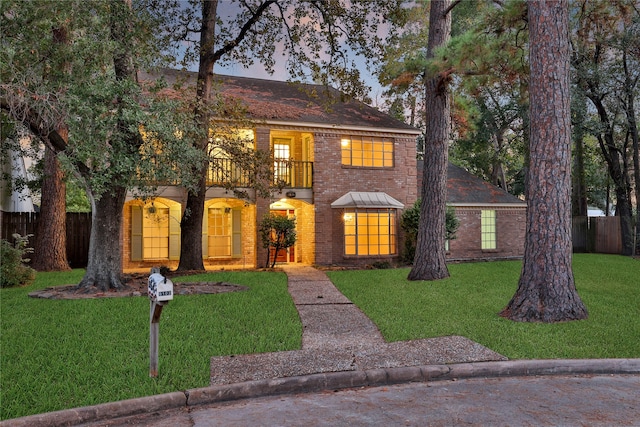 view of front of house with a balcony and a lawn