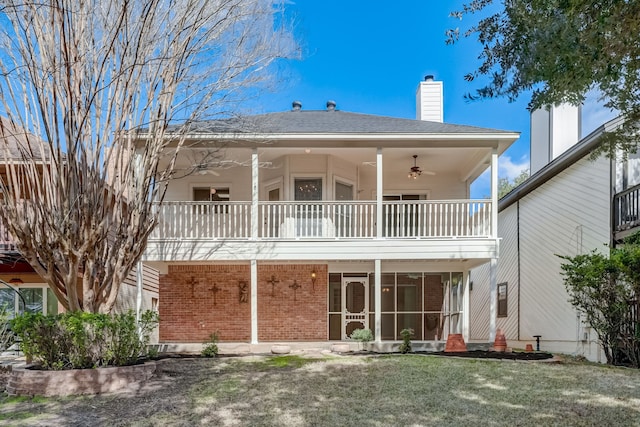 back of house featuring ceiling fan, a lawn, and a balcony