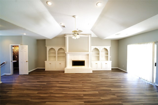 unfurnished living room with a textured ceiling, a tiled fireplace, ceiling fan, vaulted ceiling, and dark hardwood / wood-style floors