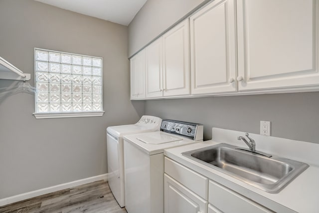 clothes washing area featuring light hardwood / wood-style floors, washing machine and dryer, sink, and cabinets