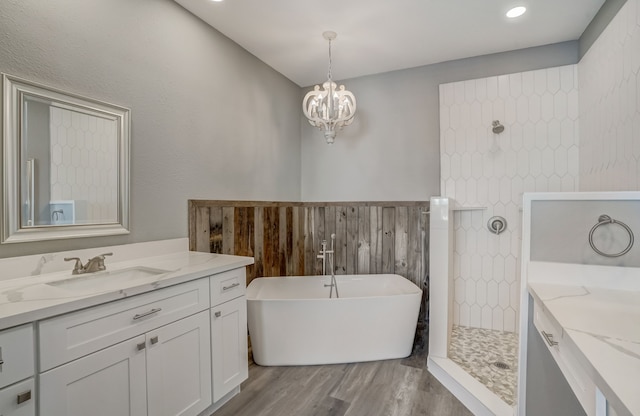 bathroom featuring vanity, wood-type flooring, an inviting chandelier, and separate shower and tub