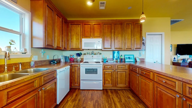 kitchen featuring white appliances, sink, kitchen peninsula, decorative light fixtures, and dark hardwood / wood-style floors