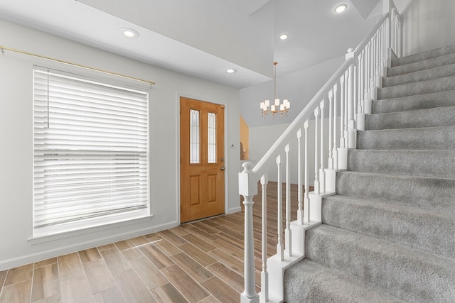 entrance foyer featuring hardwood / wood-style flooring, an inviting chandelier, and lofted ceiling