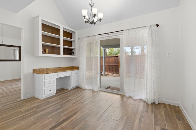 unfurnished office with built in desk, an inviting chandelier, and lofted ceiling