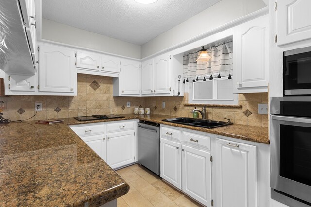 kitchen featuring backsplash, white cabinets, sink, a textured ceiling, and stainless steel appliances