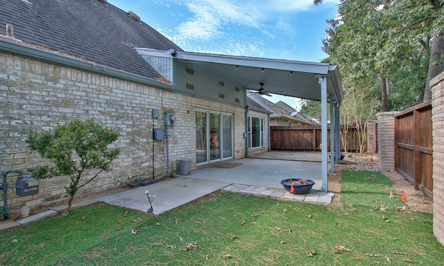 back of property featuring ceiling fan, a patio area, and a lawn