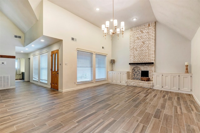 unfurnished living room featuring high vaulted ceiling, an inviting chandelier, and a brick fireplace