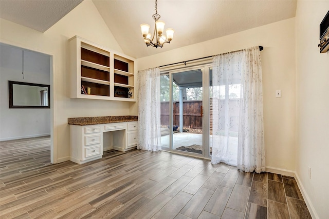 unfurnished office featuring built in desk, vaulted ceiling, and a notable chandelier