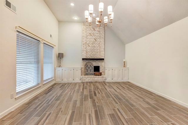 unfurnished living room featuring a fireplace, high vaulted ceiling, and an inviting chandelier