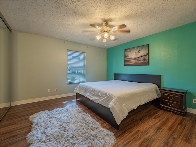 bedroom with a textured ceiling, dark wood-type flooring, and ceiling fan