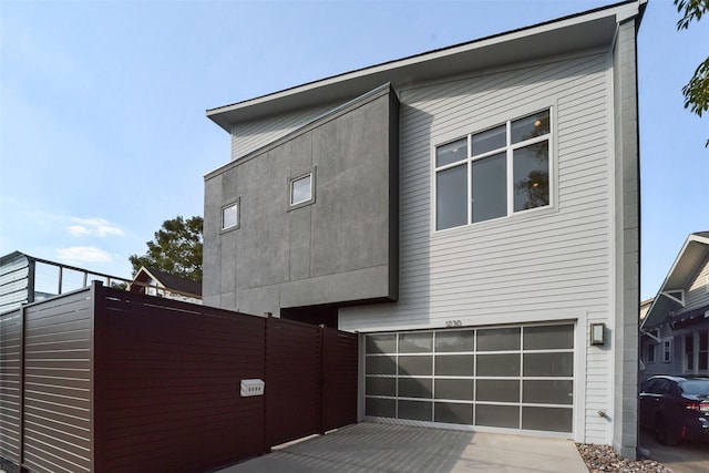 view of home's exterior with concrete driveway, fence, and a garage