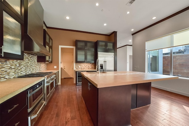 kitchen featuring a warming drawer, visible vents, stainless steel built in fridge, wall chimney range hood, and ornamental molding