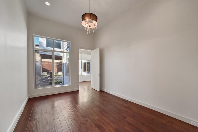 unfurnished room featuring baseboards, dark wood-style floors, an inviting chandelier, and recessed lighting