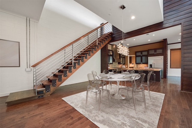 dining space with dark wood-type flooring, crown molding, a towering ceiling, and a chandelier