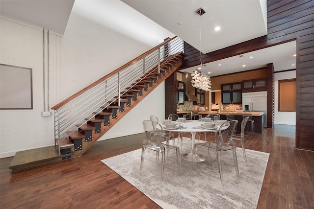 dining room with dark wood-type flooring, baseboards, stairs, and an inviting chandelier