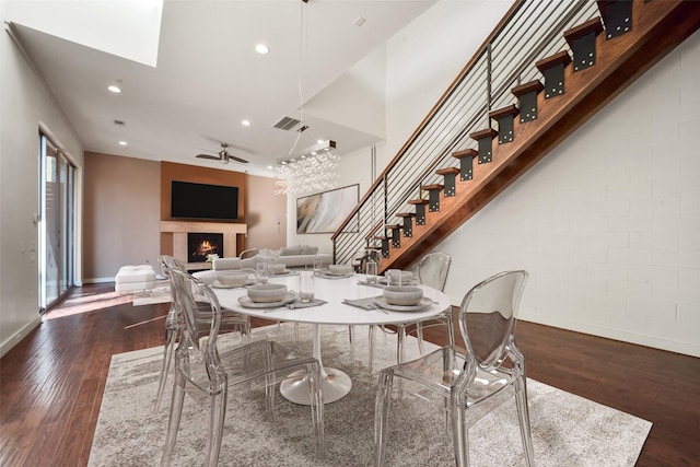 dining room with dark wood finished floors, baseboards, a lit fireplace, and recessed lighting