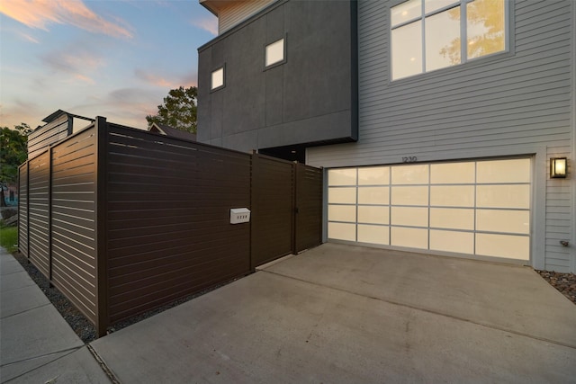 property exterior at dusk featuring an attached garage and driveway