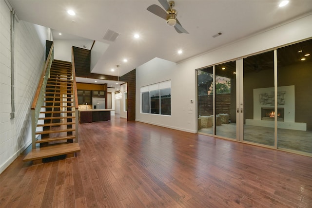 unfurnished living room featuring ceiling fan, a lit fireplace, wood finished floors, and visible vents