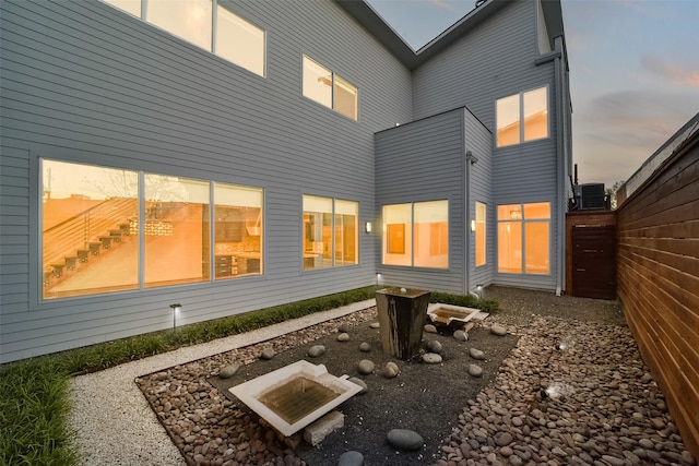 rear view of property featuring central air condition unit and fence