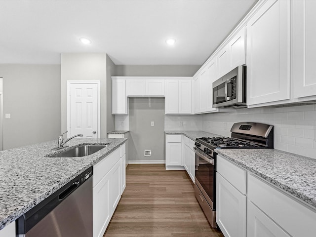 kitchen with light stone countertops, stainless steel appliances, light wood-type flooring, white cabinets, and sink