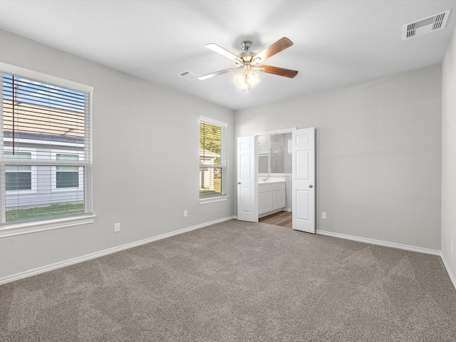 unfurnished bedroom featuring ceiling fan, ensuite bathroom, and carpet floors