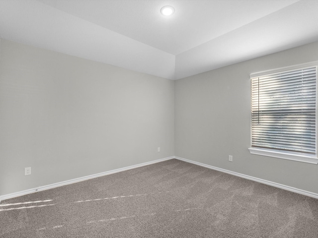 carpeted spare room with vaulted ceiling