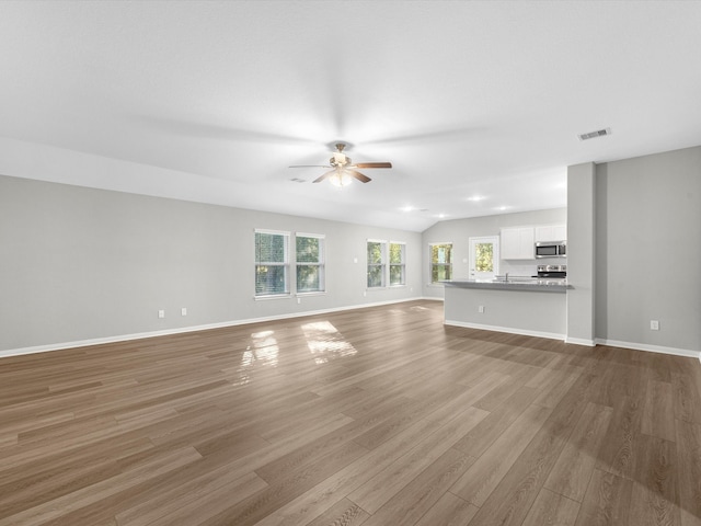 unfurnished living room with ceiling fan, wood-type flooring, and vaulted ceiling