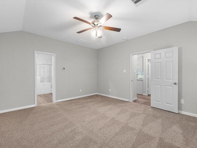 unfurnished bedroom with ensuite bath, light colored carpet, vaulted ceiling, and ceiling fan